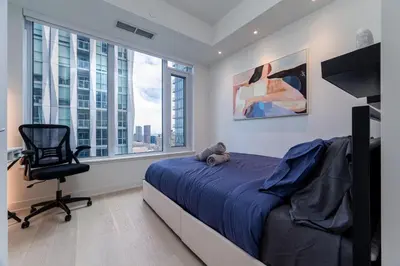 a bedroom with a bed and a chair and windows at Stylish Yorkville Condo Sleeps 3 Prime Location in Toronto