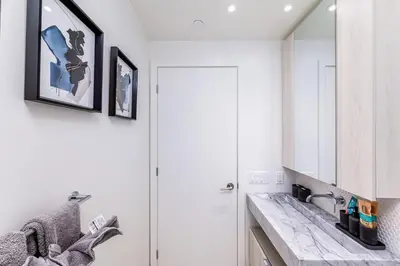 a white bathroom with a sink and a mirror at Stylish Yorkville Condo Sleeps 3 Prime Location in Toronto