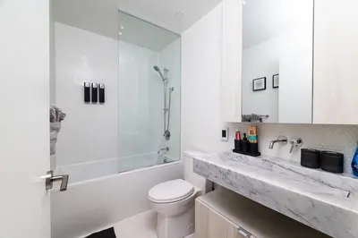 a white bathroom with a toilet and a sink at Luxury Yorkville Two Bedroom Condo With Views and Parking in Toronto