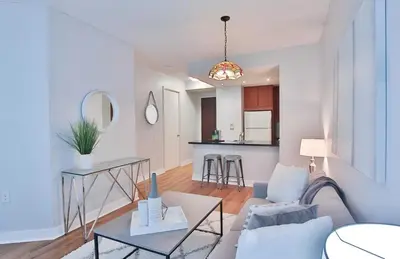 a living room with a couch and a table at Bloor Yonge Cozy 1BR And Den Free Parking in Toronto