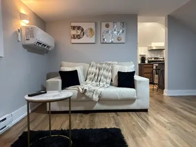 a living room with a white couch and a table at Modern 1 Bdrm with Laundry, BBQ, Deck in Welland