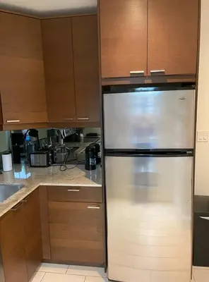 a stainless steel refrigerator in a kitchen with wooden cabinets at 2 Bed Apartment in DT Toronto with Free Parking in Toronto
