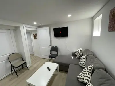 a living room with a couch and a tv on the wall at The Pantry Suite - Cozy Basement Stay in Mississauga