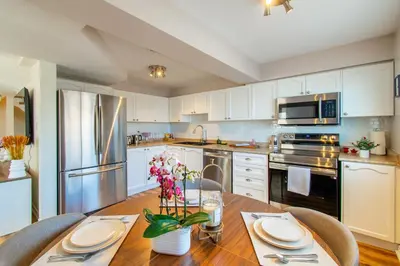 a kitchen with white cabinets and a wooden table at Cozy Barrie retreat near lake Simcoe and parks in Barrie
