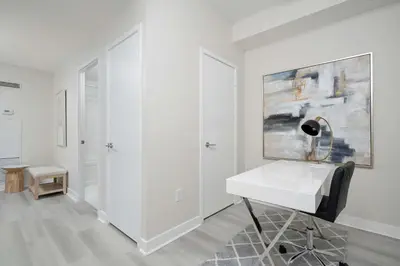 a white room with a desk and a painting on the wall at Modern CityPlace 2BR Balcony & Free Parking in Toronto