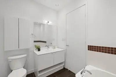 a white bathroom with a toilet and a sink at Luxury Parklawn Penthouse Breathtaking Lake View in Toronto