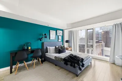 a bedroom with blue walls and a bed and a desk at Downtown Oasis Sleek Suite by Yonge Dundas Sq in Toronto