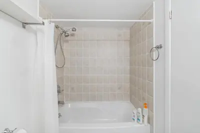 a bathroom with a white tub and a shower at Downtown Oasis Sleek Suite by Yonge Dundas Sq in Toronto
