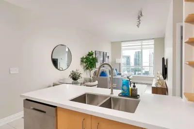 a kitchen with a sink and a living room at Bright 1BR Suite with Patio & CN Tower Views in Toronto