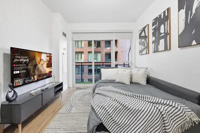 a bedroom with a large bed and a flat screen tv at Cozy 1BR Condo w Private Patio for Morning Coffee in Toronto