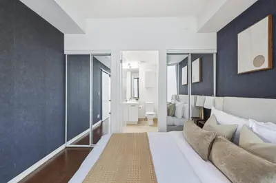 a bedroom with a large white bed and blue walls at Designer Bay Street Condo Sleep 6 in Toronto