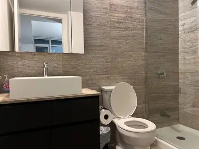 a bathroom with a toilet and a sink and a mirror at RivetStays - Dan Leckie Suite in Toronto