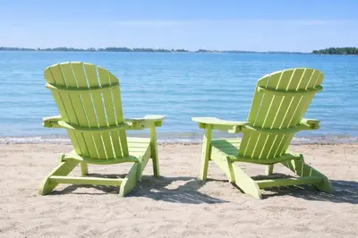 two green chairs sitting on the sand on the beach at Sandbanks Beach Cottage in West Lake