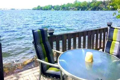 a table and chairs on a deck next to the water at Sandbanks Beach Cottage in West Lake