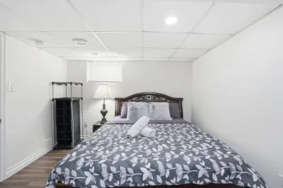 a bedroom with a bed with a black and white comforter at 5 Bedroom House - 1 Block from the Falls in Niagara Falls