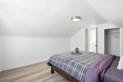 a white bedroom with a bed with a stuffed animal on it at 5 Bedroom House - 1 Block from the Falls in Niagara Falls