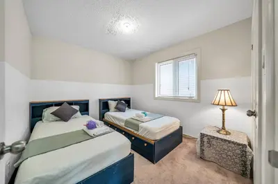 a bedroom with two beds and a lamp and a window at Exhilarating Castle Vibes In Toronto Area in Ajax