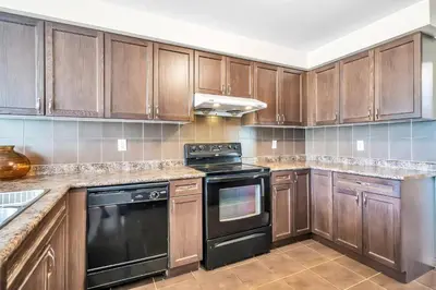 a kitchen with wooden cabinets and black appliances at Exhilarating Castle Vibes In Toronto Area in Ajax