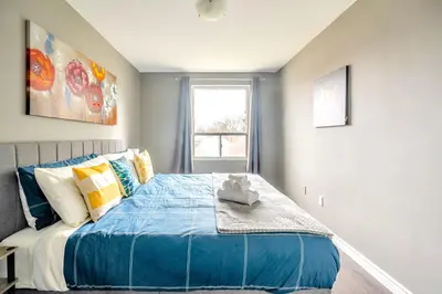 a bedroom with a bed with blue sheets and a window at Charming Newly Renovated Condo - Glenview West in Hamilton
