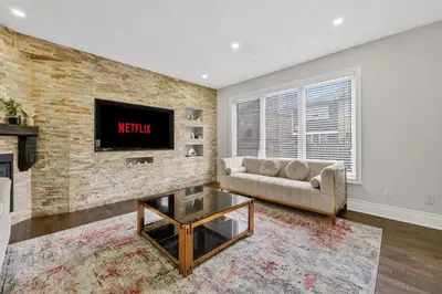 a living room with a couch and a tv on a brick wall at Spacious Modern 5BR Home Sleeps 13 Family home in Milton