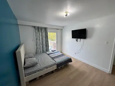 a bedroom with a bed and a tv on a wall at Private Room Near Airport D12 in Mississauga