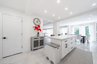 a large white kitchen with a clock on the wall at Licensed-8 Acre Estate, Trail & Stream with 3 Beds in Hamilton
