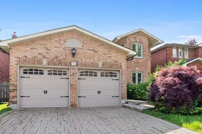 a brick house with two garage doors at Modern 4BR Retreat with Premium Comforts & Parking in Richmond Hill