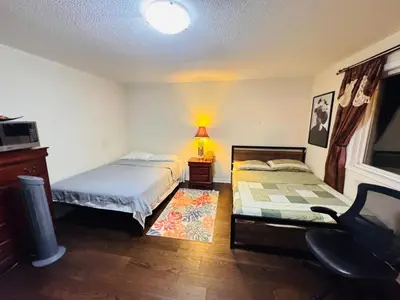 a bedroom with two beds and a lamp and a chair at Scarborough Spacious Private Suite 2 Queen Beds & Ensuite in Toronto