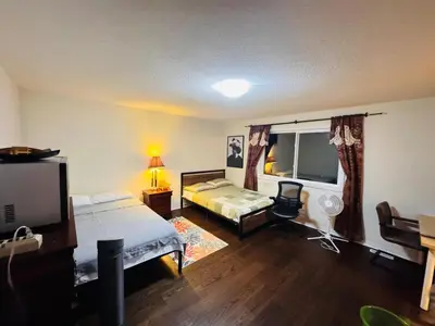 a bedroom with two beds and a desk and a television at Scarborough Spacious Private Suite 2 Queen Beds & Ensuite in Toronto