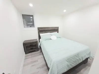 a white bedroom with a bed and a night stand at Niagara Cozy Suite - Modern 2Bed 15 min to Falls in Thorold