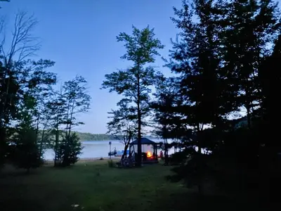 a gazebo with a tent next to a lake at Dudley House Lakeside Retreat with Access to Private Beach in Haliburton