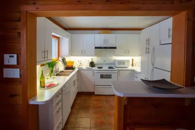 a kitchen with white cabinets and white appliances at Dudley House Lakeside Retreat with Access to Private Beach in Haliburton