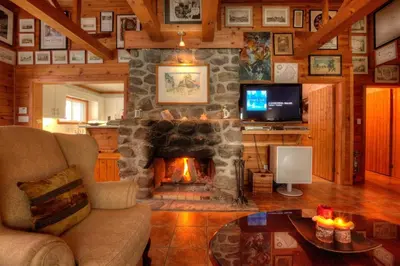 a living room with a stone fireplace and a television at Dudley House Lakeside Retreat with Access to Private Beach in Haliburton