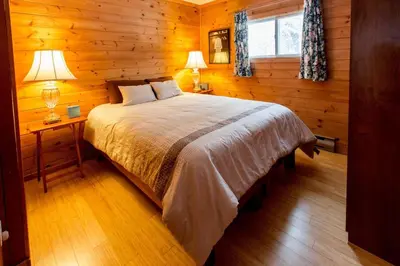 a bedroom with a bed and two lamps and a window at Dudley House Lakeside Retreat with Access to Private Beach in Haliburton