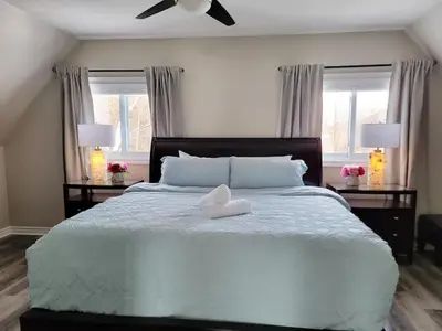 a bedroom with a large bed with two windows at Private Ski Chalet Hot Tub & Mountain Views in Blue Mountains