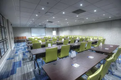 a conference room with tables and chairs and a screen at Holiday Inn Express & Suites Toronto Airport West by IHG in Mississauga