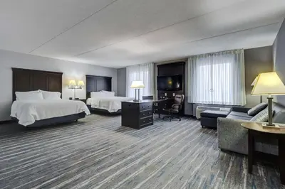 a hotel room with two beds a desk and a couch at Hampton Inn & Suites by Hilton Brantford in Brantford