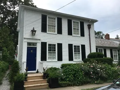 a white house with black shutters and a blue door at Dot's Landing Garden Room in Niagara on the Lake