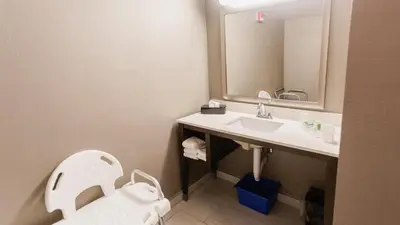 a bathroom with a sink and a toilet and a mirror at Holiday Inn Hotel Peterborough Waterfront by IHG in Peterborough