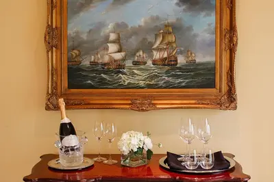 a table with wine glasses and a painting of ships at Riverbend Inn & Vineyard in Niagara on the Lake