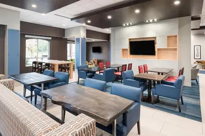 a dining room with tables and chairs and a flat screen tv at Holiday Inn Express Hotel & Suites Milton by IHG in Milton