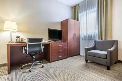 a hotel room with a desk and a chair and a television at Comfort Inn & Suites in Collingwood
