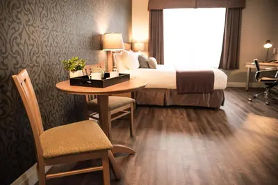 a hotel room with a bed and a table and chair at Cambridge Hotel and Conference Centre in Cambridge
