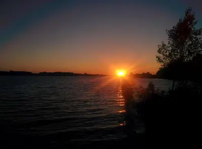 a sunset over a body of water with the sun setting at All Tucked Inn in Waubaushene