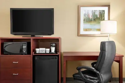 a room with a desk and a chair and a television at Travelodge by Wyndham Oshawa Whitby in Oshawa