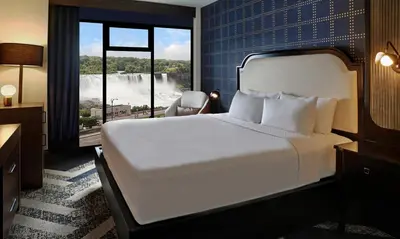 a hotel room with a bed and a view of a waterfall at The Brock Niagara Falls Fallsview, Tapestry by Hilton in Niagara Falls
