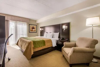 a hotel room with a bed and a chair at Comfort Inn Airport West in Mississauga