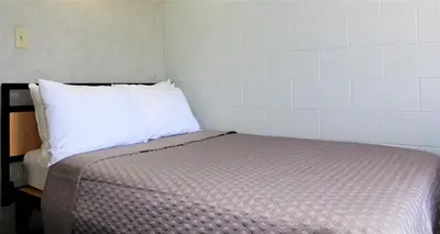 a small bedroom with a bed with a white pillow at Residence & Conference Centre - Welland in Welland