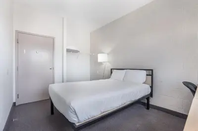 a bedroom with a white bed with a mirror at Residence & Conference Centre - Niagara-on-the-Lake in Niagara on the Lake