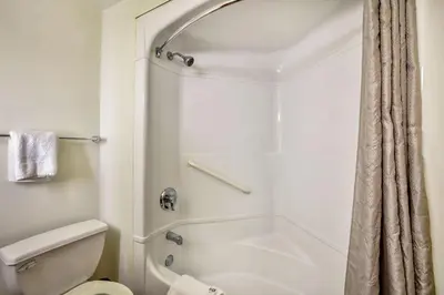 a white bathroom with a shower and a toilet at Motel 6-Burlington, ON - Toronto West - Oakville in Burlington